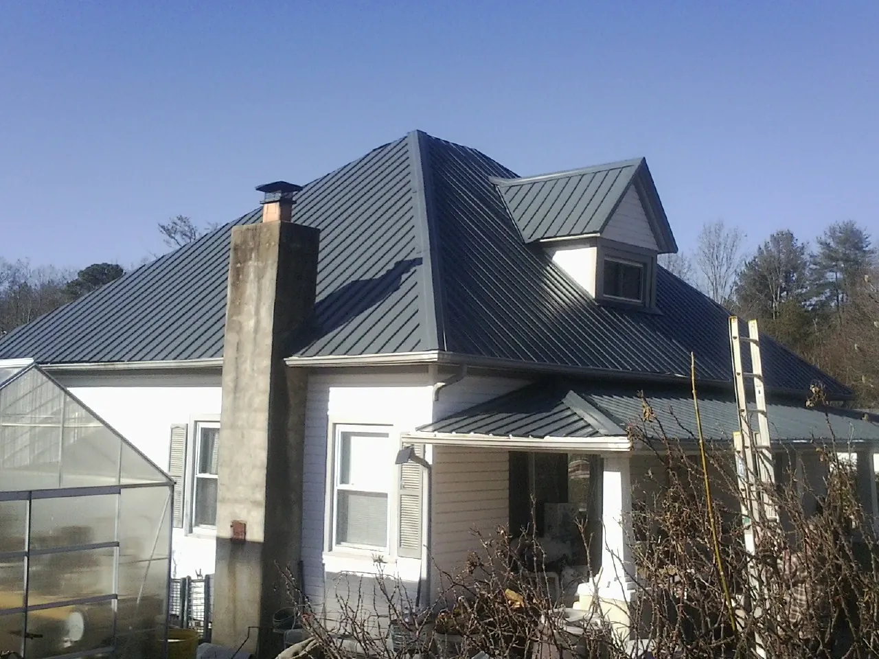 Dark blue standing seam metal roof on a white farmhouse with dormer — Slate & Tile Roof Repair by Roofing Brothers in Roselle