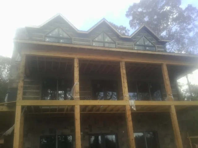 Dormers and porch framing on a large log home under construction — Roof Coating work by our crew in Roselle