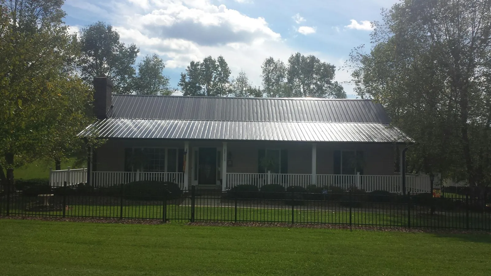 Gray metal roof on a brick ranch with a full width front porch — Gutter Guard Installation work by our crew in Roselle